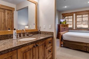 Your suite bathroom features a granite vanity with premium amenities, creating a seamless flow with the spacious bedroom and natural wood accents throughout.