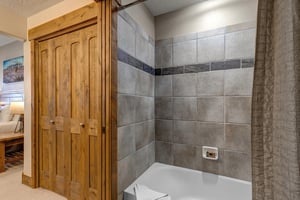 Step into your private bathroom featuring elegant gray tile work and a deep soaking tub where you can unwind after mountain adventures.