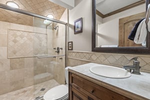 Unwind in your elegantly tiled bathroom featuring a spacious walkin shower and rich wooden vanity details.