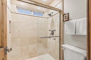 Step into your private spalike retreat with travertine tiles, rainfall showerhead, and fluffy towels.
