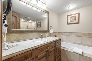 Unwind in your private bathroom featuring warm wood vanity and soaking tub.