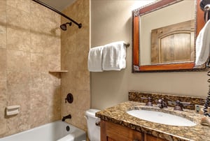Unwind in your elegant bathroom featuring travertine tiles, granite countertops, and plush towels for your comfort.