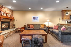 Unwind in your cozy living room with warm fireplace glow, two plush couches, and rustic charm.
