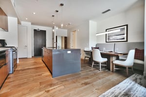 Solid quartz kitchen island with pendant drop lighting with the kitchen and dining area on either side