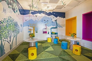 Kids lounge in the Lift clubroom, colorful play tables and decorative paintings of chairlifts on the wall