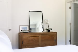 Queen guest bedroom with wooden chest and large vanity mirror