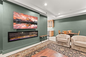 Cozy up in your elegant living space featuring a modern fireplace and large TV, perfect for relaxing evenings together.