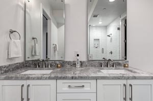 Refresh in the ensuite bathroom with dual vanities, marble countertops, and walkin shower.