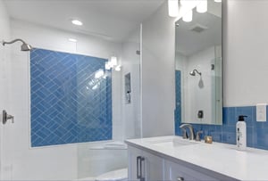 The shared bathroom featuring a gorgeous blue herringbone tile shower and sleek modern finishes.
