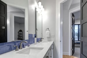 Fresh white towels await you in this sleek bathroom with dual sinks and modern touches.