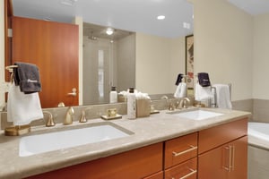 En suite bathroom with double sink wooden vanity and a large mirror spanning the length of the vanity.