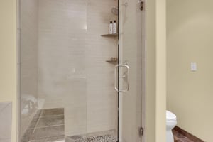 Walkin shower with tile surround, tile sitting bench, and glass enclosure.