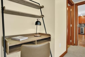 A black and wood desk shelves above, task lighting, and a leather chair.