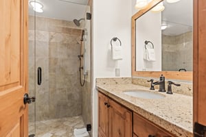 The shared bathroom has a single sink, and a wood vanity with a granite counter top.
