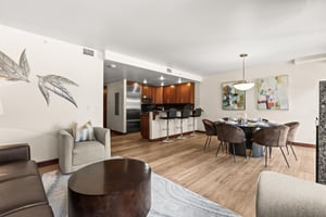 A stylish openplan living space featuring warm wood floors, contemporary art, and a fully equipped kitchen.