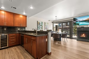 The sleek kitchen flows into a cozy dining space with crackling fire to create the perfect mountain retreat.