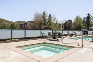 The Lowell Condos common area hot tub and a patio table with chairs to gather around on the pool deck.