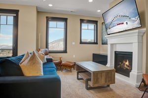 The living room with Smart TV, deep blue velvet couch and leather chair