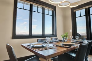 Wood dining table with leather chairs and a large window with snowy mountain views beyond.