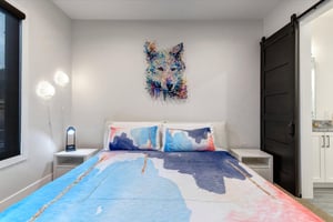 The stylish second bedroom has a vibrant painting of a wolf and matching bedding.