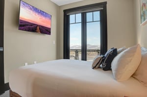 Second bedroom with a queen size bed and glass double doors that lead to a balcony with mountain views.
