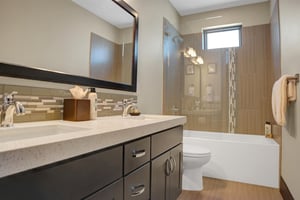 A shared bathroom with a bathtub and shower combination and dark wood cabinet with double sinks.