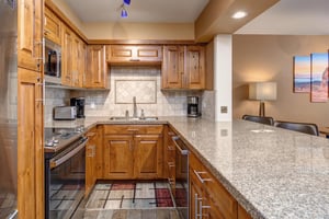 Resort Plaza 5024 offers a fully equipped kitchen featuring warm wood cabinetry, granite countertops, and modern appliances.