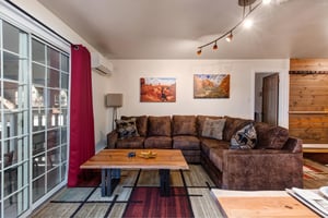 The living room features a plush sectional sofa, natural wood coffee table, and striking desert artwork.