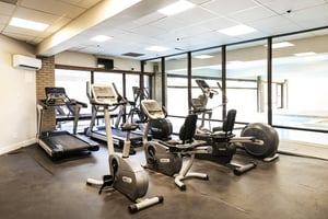 Resort Plazas fitness center with floor to ceiling window walls overlooking the pool and various workout machines.