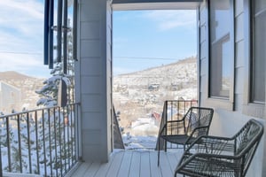 The exterior entryway has two black chairs and overlooks a snowy mountain and Historic Main Street in Park City, Utah.