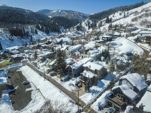 159 Woodside is surrounded by snowy homes and evergreen tree covered mountains.