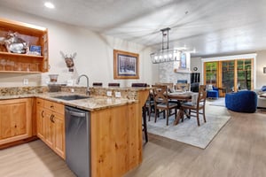 Gather around the rustic dining table in this openconcept space, where warm wood tones and granite countertops create an inviting atmosphere for your mountain retreat meals and memories.