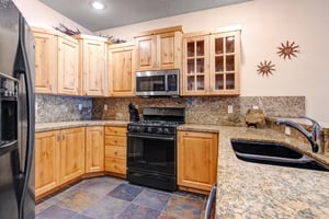 Your fully equipped kitchen features granite countertops, modern appliances, and warm wood cabinetry—perfect for preparing homemade meals during your mountain getaway.