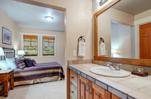 Unwind in your private suite featuring a comfortable bed with vibrant linens, warm wood accents, and an ensuite vanity with fresh towels awaiting your arrival.