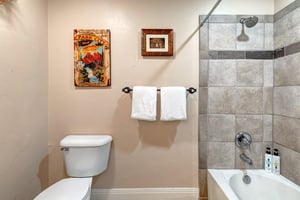 Freshen up in your private bathroom with a modern tiled showertub combo, plush white towels, and thoughtful touches like vintage artwork to make your stay feel special.