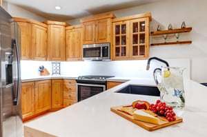 This Park City Lodging vacation rental offers a fullyequipped kitchen with white countertops and warm wood cabinetry.