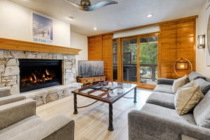 Town Pointe B102 offers a living room, where a warm stone fireplace and plush seating create the perfect aprèsski retreat.