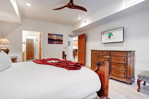 Drift off under a wooden ceiling fan in this bright bedroom, where crisp linens and warm wood furnishings create a cozy alpine retreat youll love coming home to.