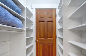 Spacious walkin closet with custom white shelving.