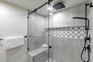 The private en suite bathroom features a spalike shower, elegant gray tiling and a builtin bench for comfort.