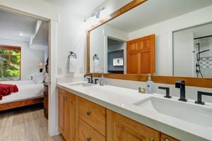 Your ensuite bathroom features double sinks, warm wood cabinetry, and a sleek marble countertop.