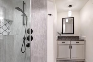A sleek walkin shower featuring modern fixtures and elegant tiling, paired with a stylish vanity.