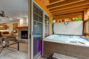 Step through open doors to your private hot tub, where warm bubbling jets and ambient lighting await under a sheltered wooden deck—relaxation just steps from your cozy living room.