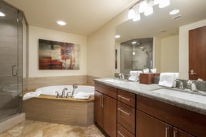 Ensuite full bathroom, deep soaker tub enclosed in sandstone tile, double vanity bathroom with single panel mirror