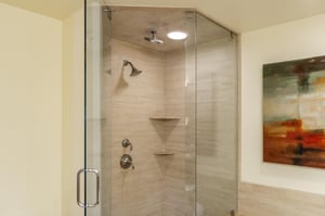 Main bathroom shower, sandstone tile walls and glass paneled door and wall