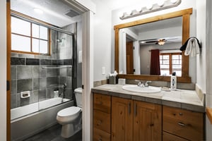 Ensuite full guest bathroom, tiled countertops and shower, wooden cabinets