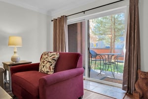 Park Station 113s living room has a red love seat and has sliding glass doors behind it leading to a private patio.