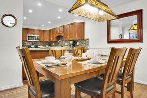 Park Station 113 has a wood dining table, six wood chair, place settings for 6 and is open to the kitchen area.