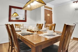 Park Station 113 has a wood dining table, six wood chair, place settings for 6 and the entry way area is behind.