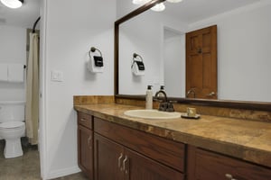 The shared bathroom has a one sink vanity, and separate water closet with a bathtub and shower combination.